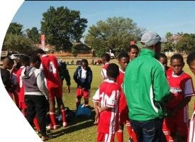 A coach talking with young players on the pitch